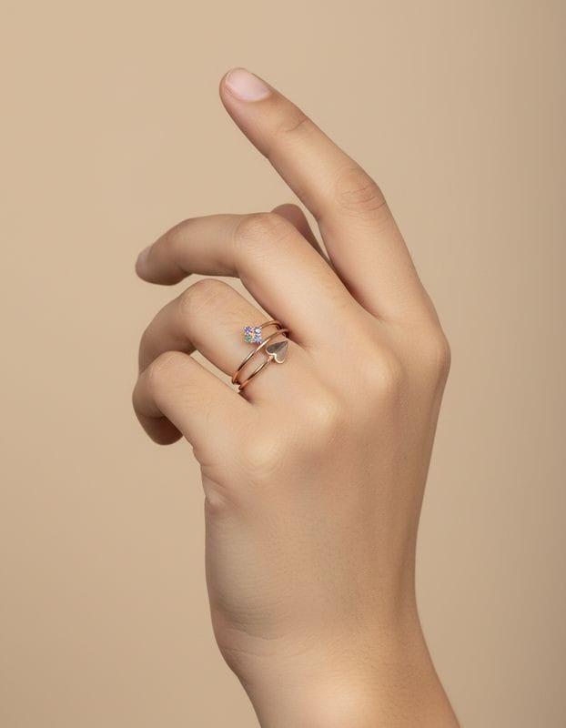 Hand wearing a ring with a blue gemstone on a beige background