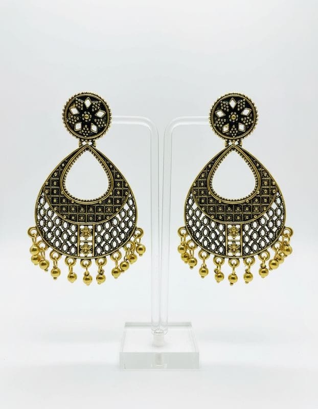 Pair of gold and black earrings on a white stand